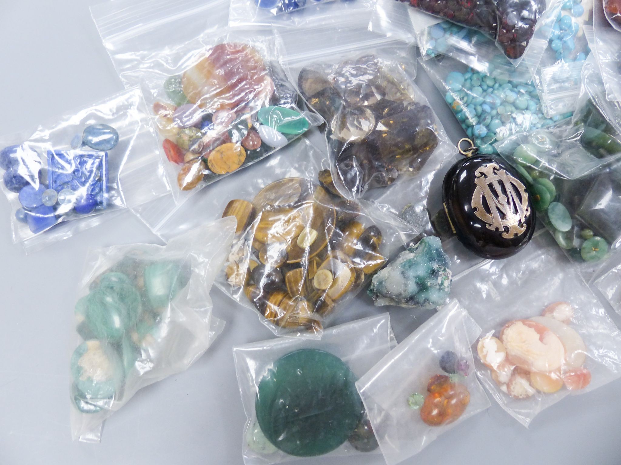 A quantity of assorted unmounted gemstones including, opal, opal doublet, malachite, chalcedony, tiger's eye quartz, hematite, etc.